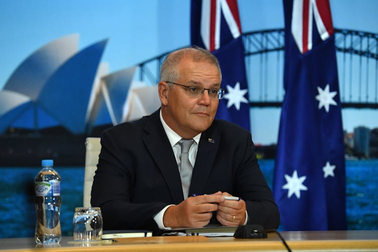 Scott Morrison in front of Sydney harbour backdrop and Australian flags