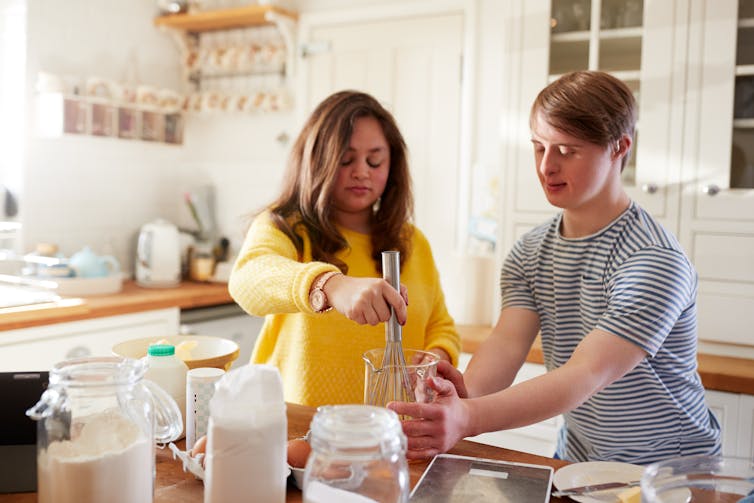 Two people with Down Syndrome cooking in the kitchen.