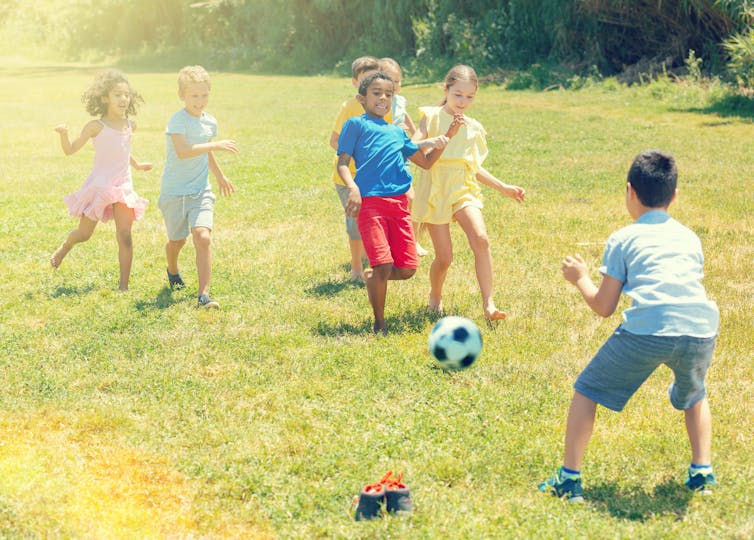 Children playing soccer outside.