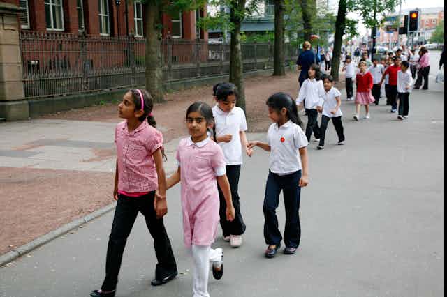 School children in uniform walk down a street in Manchester 