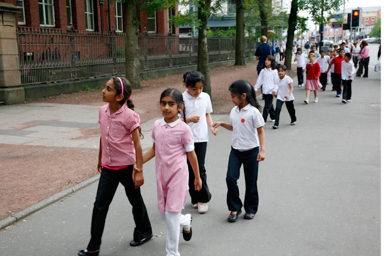School children in uniform walk down a street in Manchester