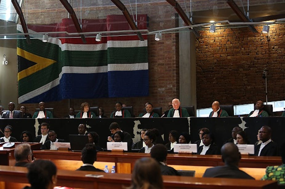 Judges and clerks with flag on the wall behind their seats