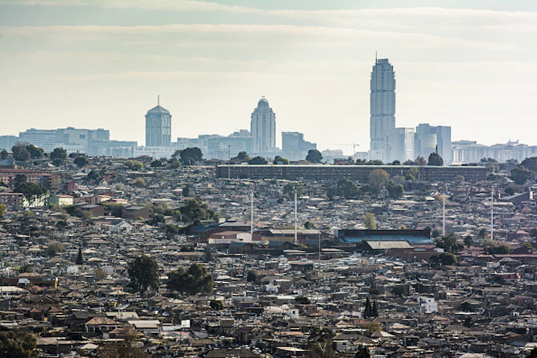 View of slum housing in the foreground and tall commercial buildings in the background