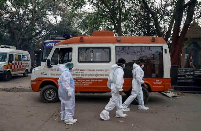 Relatives of COVID-19 victims walk past a van at Nigambodh Ghat crematorium in New Delhi