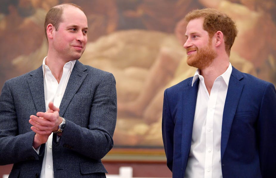 Prince William and Prince Harry looking at each other and smiling.