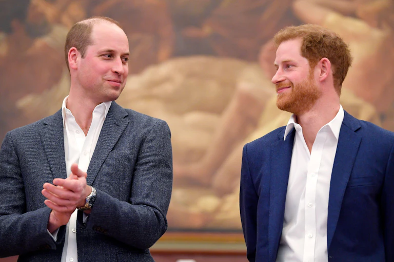 Prince William and Prince Harry looking at each other and smiling.