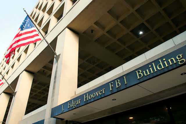 Close-up of the entrance to the FBI's J. Edgar Hoover headquarter building in Washington, DC with the building's name plaque and a flag