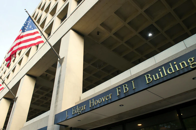 Close-up of the entrance to the FBI's J. Edgar Hoover headquarter building in Washington, DC with the building's name plaque and a flag