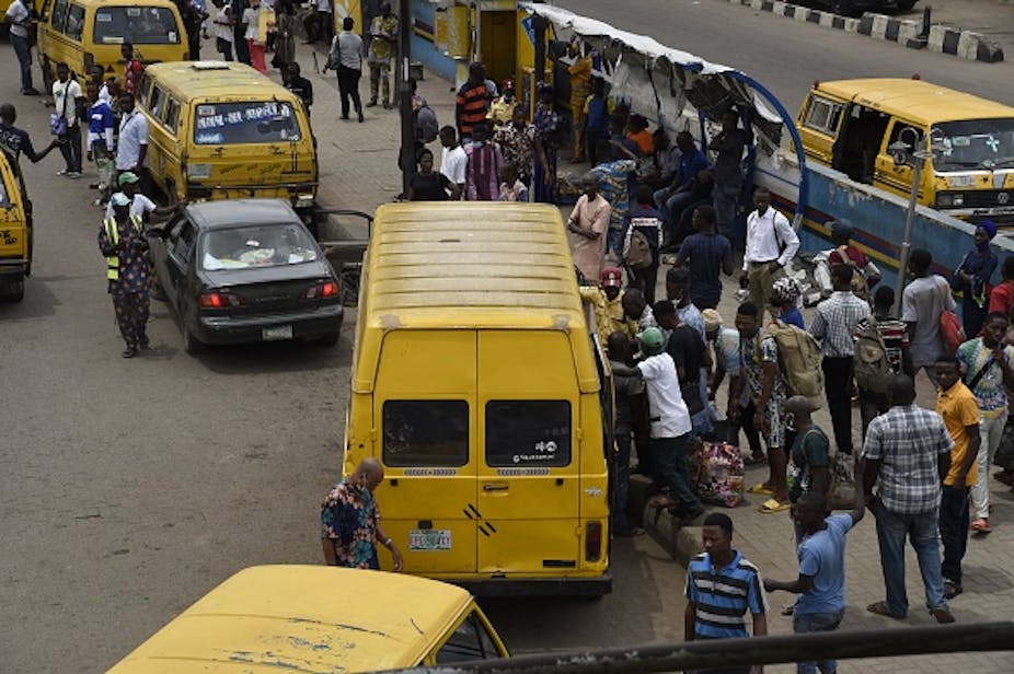 People scrambling to board a passenger bus on a road.