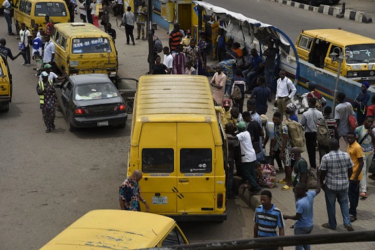 People scrambling to board a passenger bus on a road.