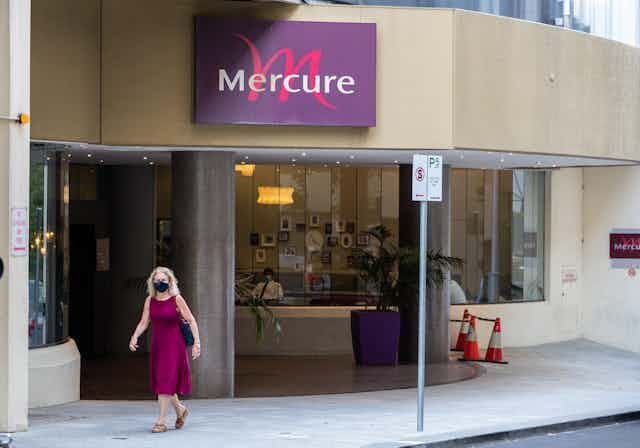 Woman wearing mask walks past Perth's Mercure hotel