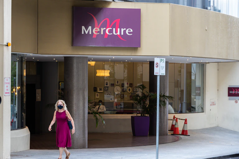 Woman wearing mask walks past Perth's Mercure hotel