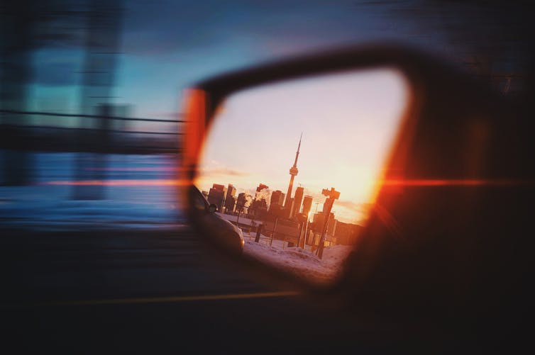 The CN Tower in the side-view mirror of a car