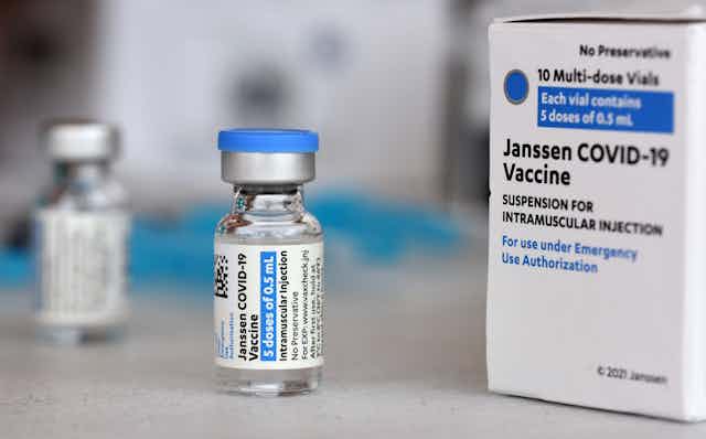 A vial of vaccine next to a box of vaccine. 