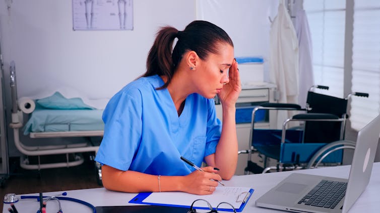 Tired nurse completes notes in ward