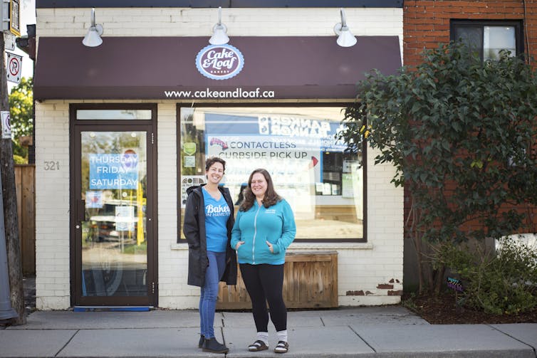 Two women stand in front of a bakery.