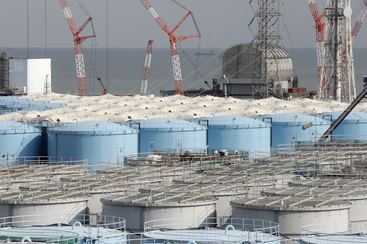 A harbour full of cranes and large water storage tanks.