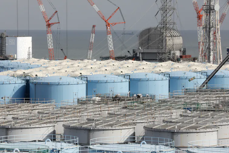 A harbour full of cranes and large water storage tanks.