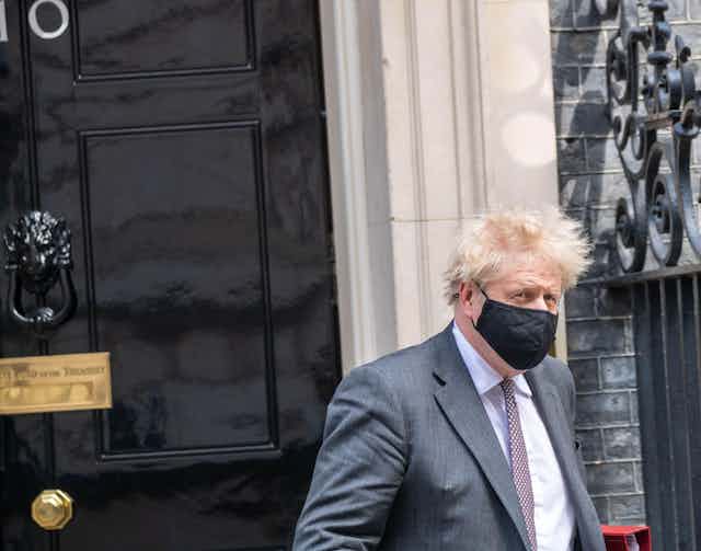 Boris Johnson leaving Downing Street wearing a face mask.