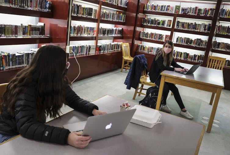 Os alunos trabalham em laptops na biblioteca do ensino médio