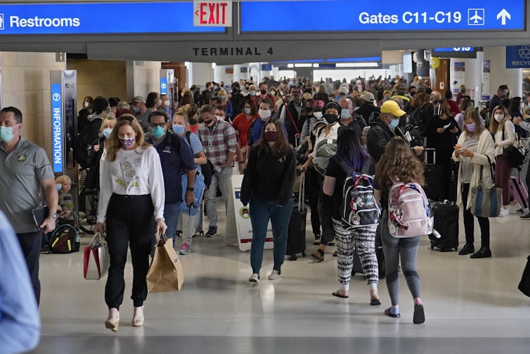 Masked passengers moving through airline terminal