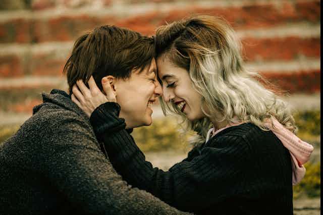Two people nose to nose, holding each other and smiling