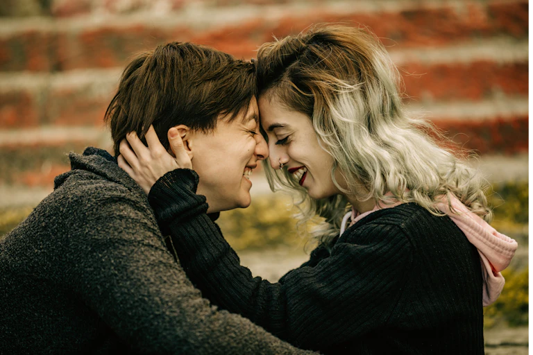 Two people nose to nose, holding each other and smiling