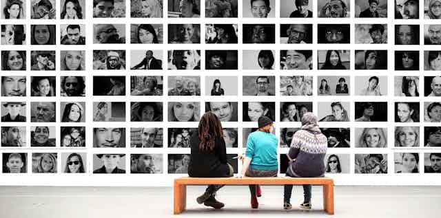 People sitting in front of a montage of faces.