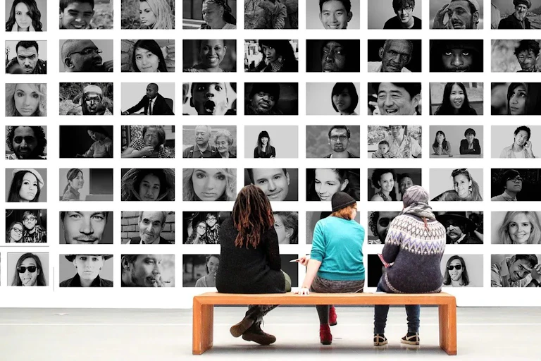 People sitting in front of a montage of faces.