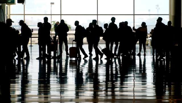 silhouettes of people with bags at an airport