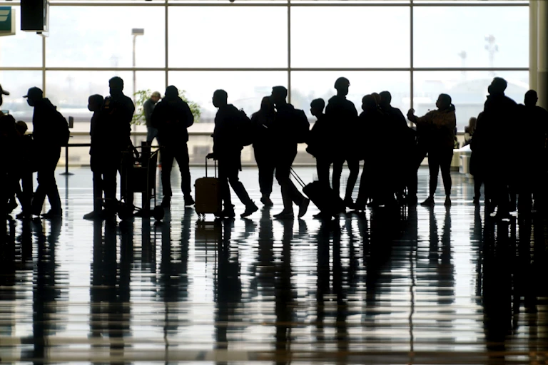 silhouettes of people with bags at an airport