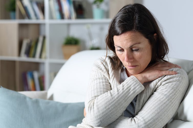 A woman sitting on the couch, appears pensive or unhappy.