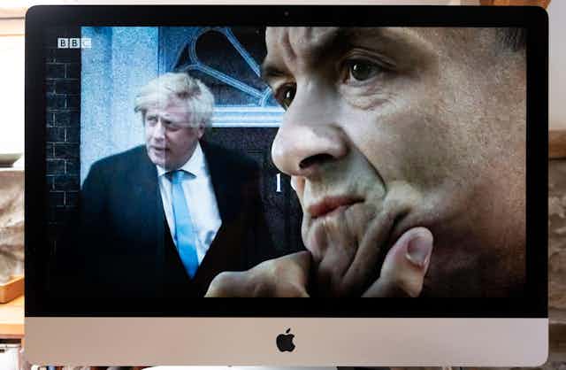 Computer screen BBC TV image of Boris Johnson outside 10 Downing Street door and Dominic Cummings seen in profile.