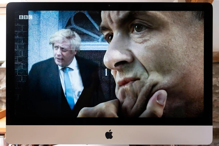 Computer screen BBC TV image of Boris Johnson outside 10 Downing Street door and Dominic Cummings seen in profile.