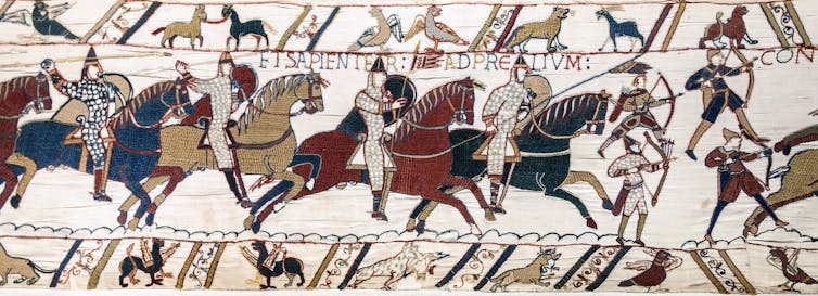 A scene from the Bayeux Tapestry depicting Norman knights on horseback, riding into battle.