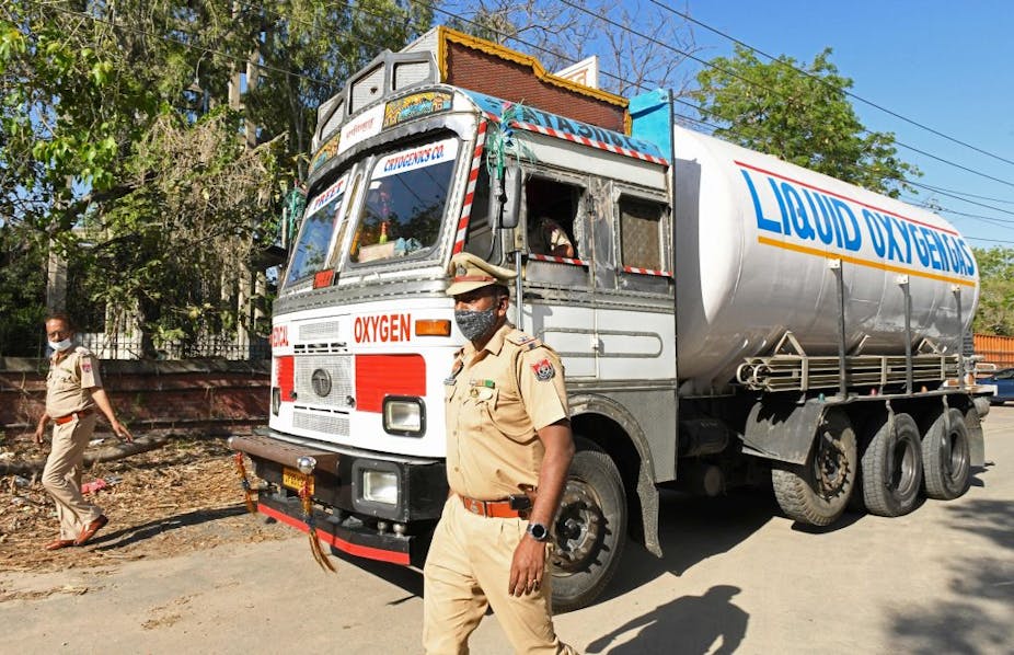 Police personnel escort a truck carrying medical liquid oxygen