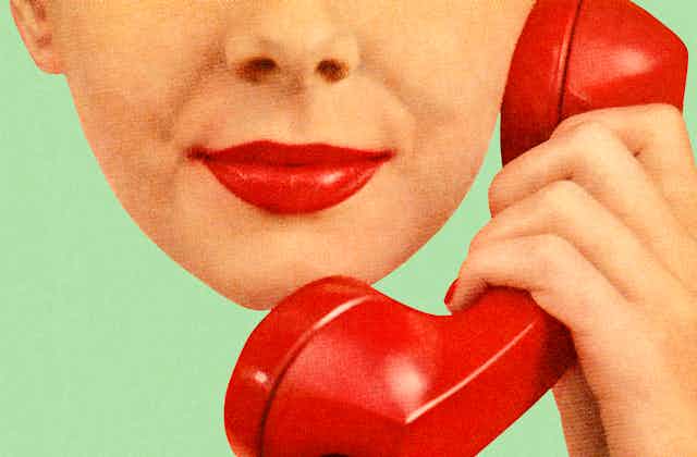 A woman with red lipsick holds a phone up to her ear.