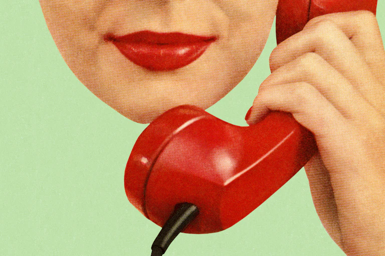 A woman with red lipsick holds a phone up to her ear.