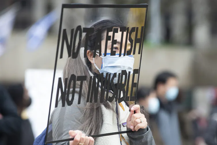 Woman stands holding protest sign