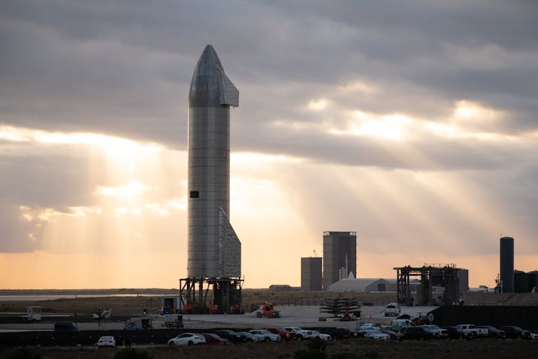 A large silver rocket that stands upright on a launch pad.