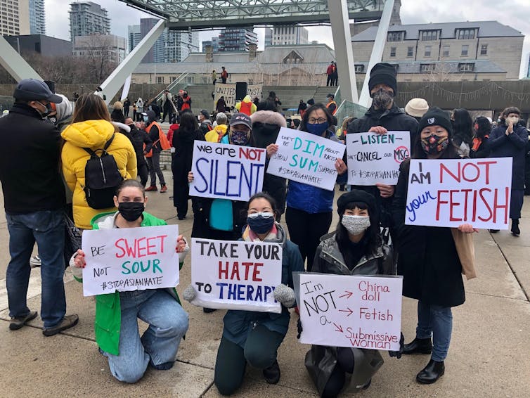 Protesters sit holding signs