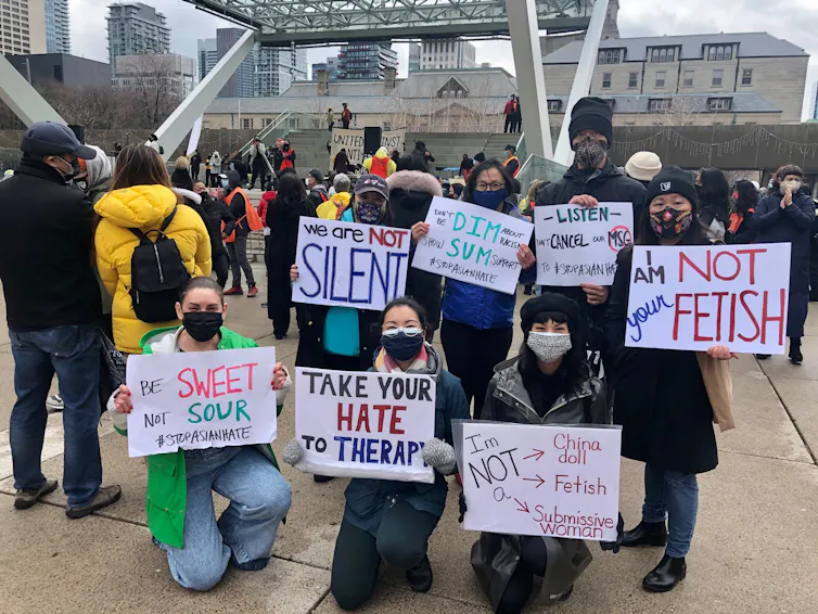 Protesters sit holding signs