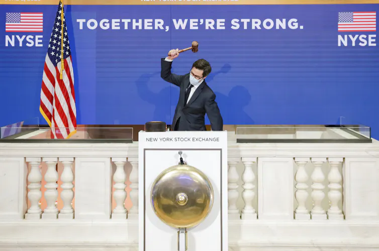 A man holding a gavel in the air above his head prepares to ring the closing bell at the New York stock exchange