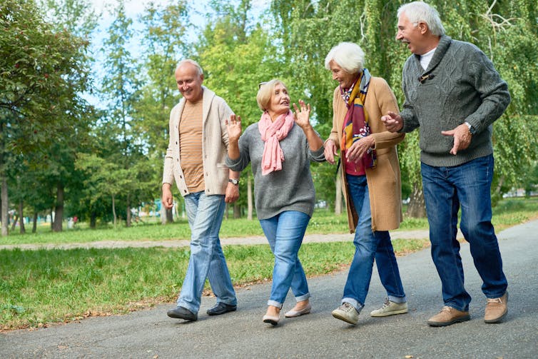 Four people chatting as they walk through a park