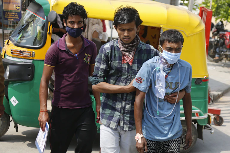 Two men supporting man with oxygen.