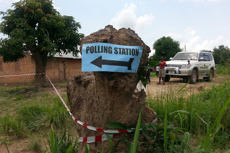 Sign for polling station fixed to a tree stump outside a rural building