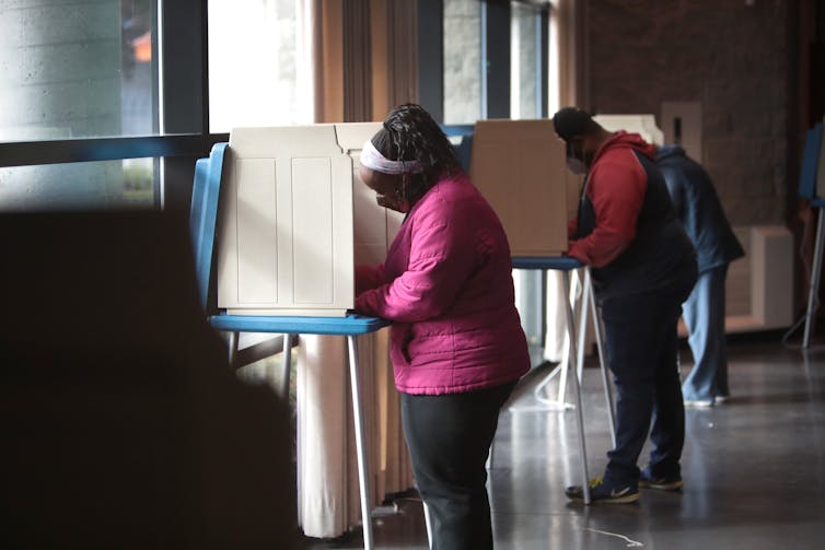 Two people voting in a large public space.