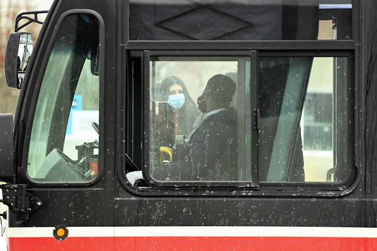 A bus driver and a passenger seen through a bus window