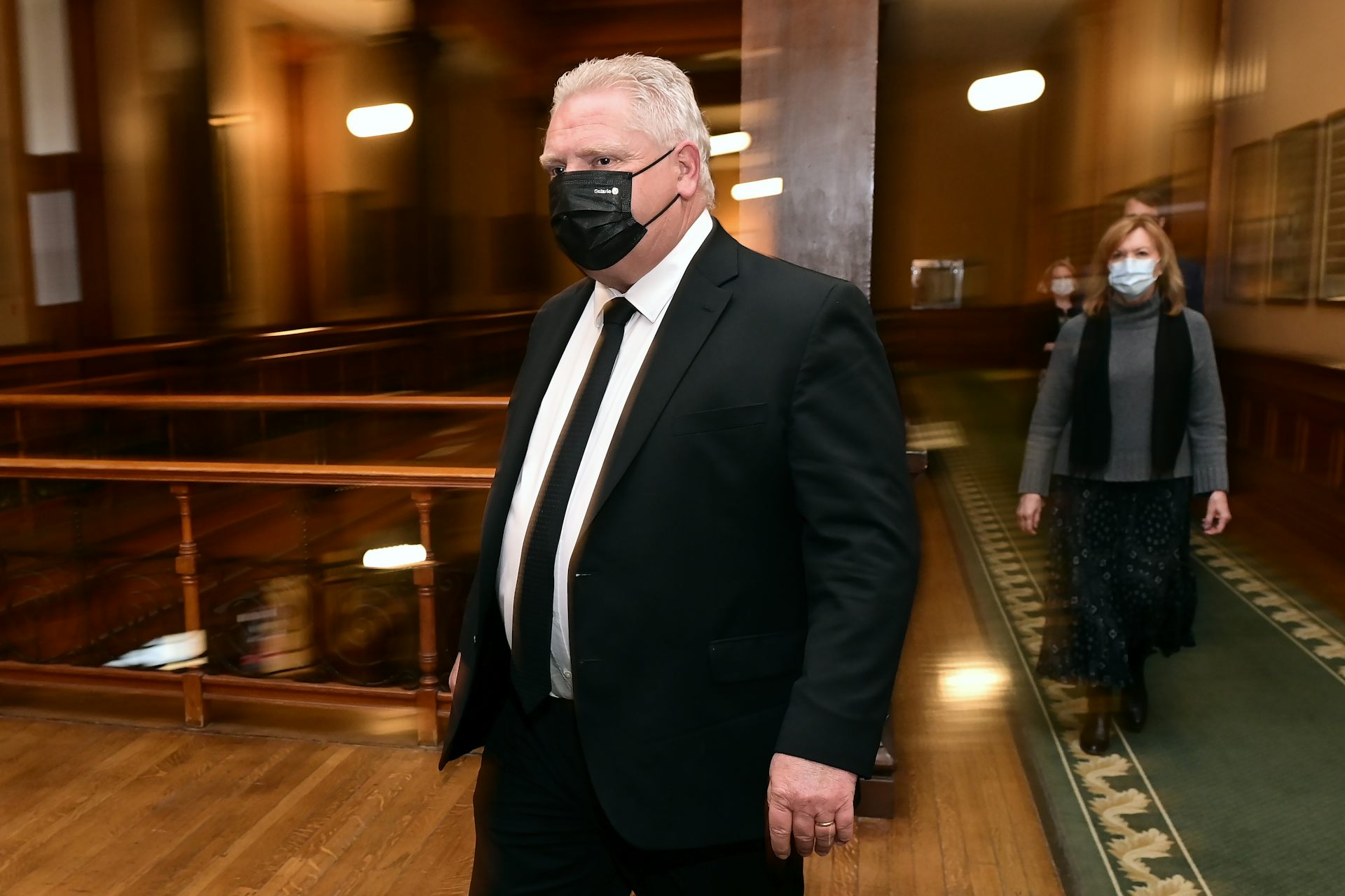 Premier Doug Ford wearing a black face mask, with Health Minister Christine Elliott in the background wearing a face mask.