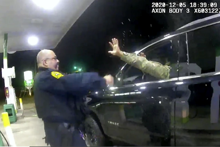 A police officer sprays a man sitting in the driver's seat of a car
